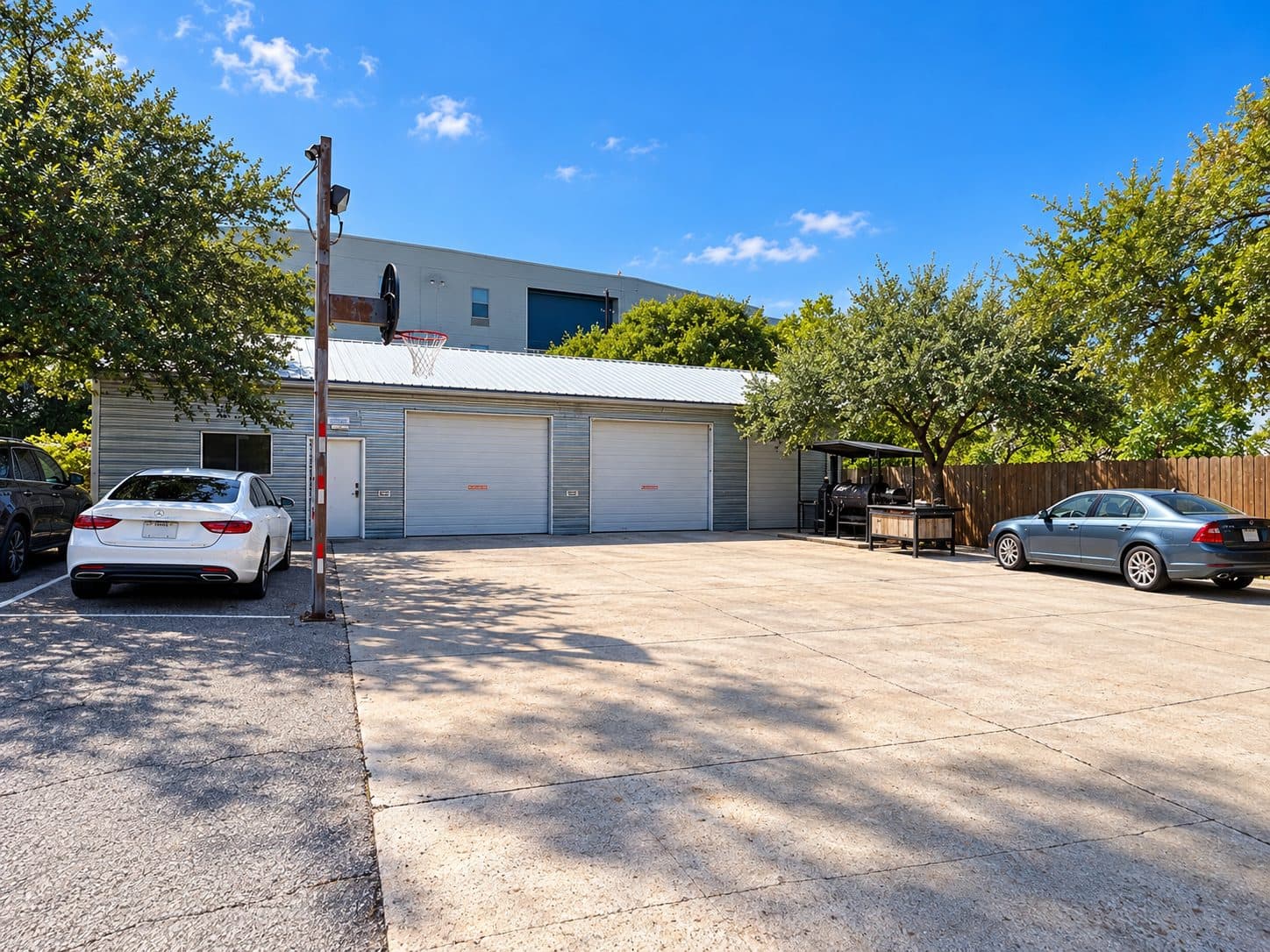 Studio building with roll-up doors, a covered BBQ area, and an open paved lot