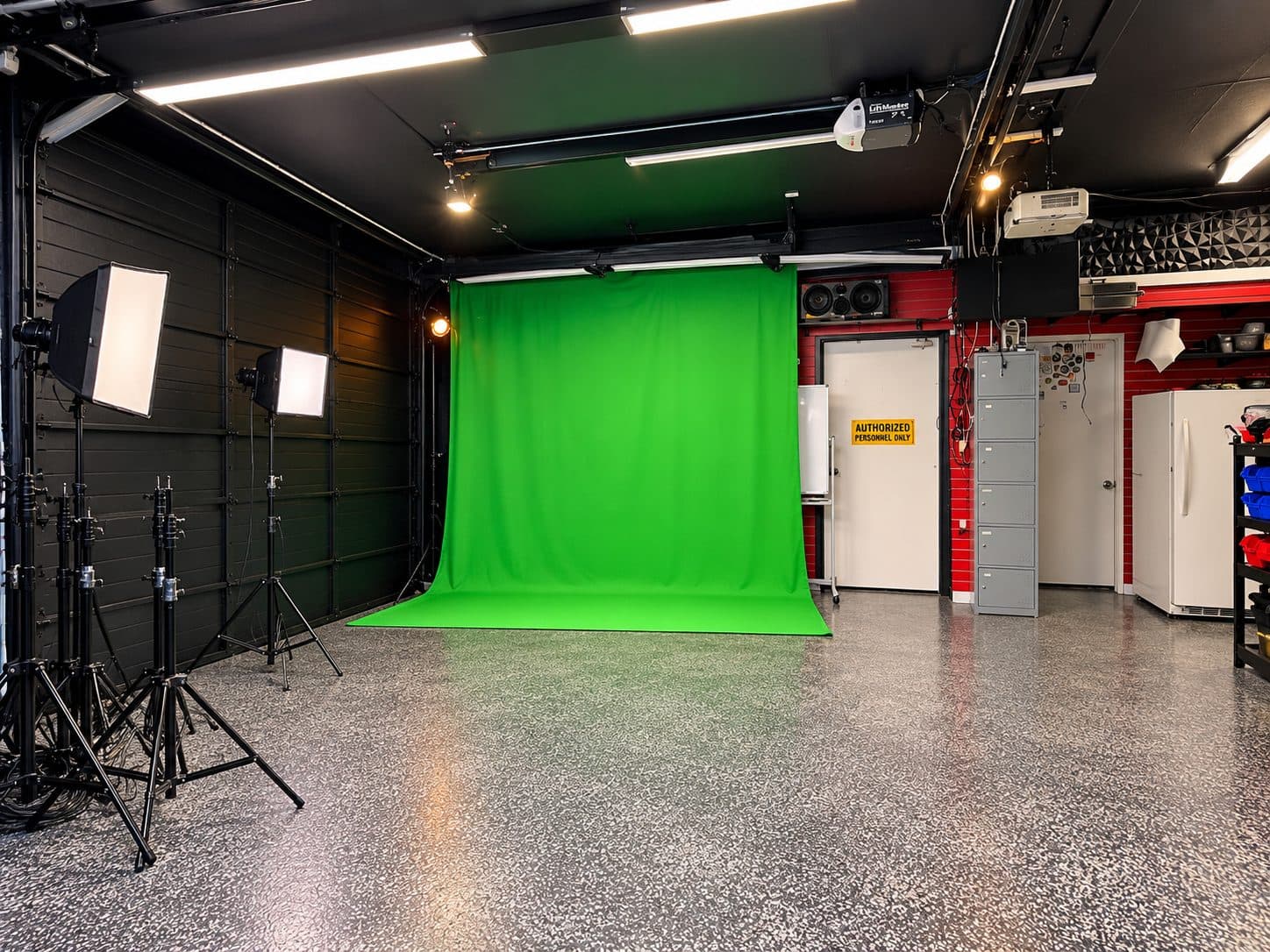 Green screen backdrop with softbox lights and C-stands next to the equipment area