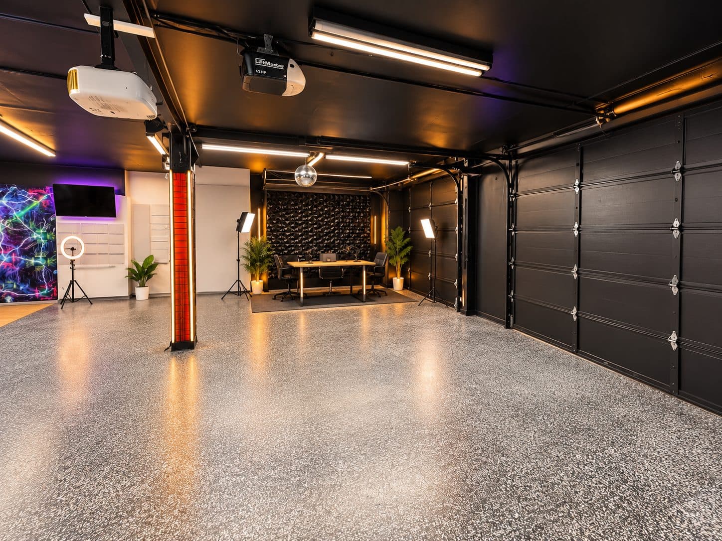 Wide open studio floor with epoxy flooring, roll-up doors, a projector, and an interview set at the back