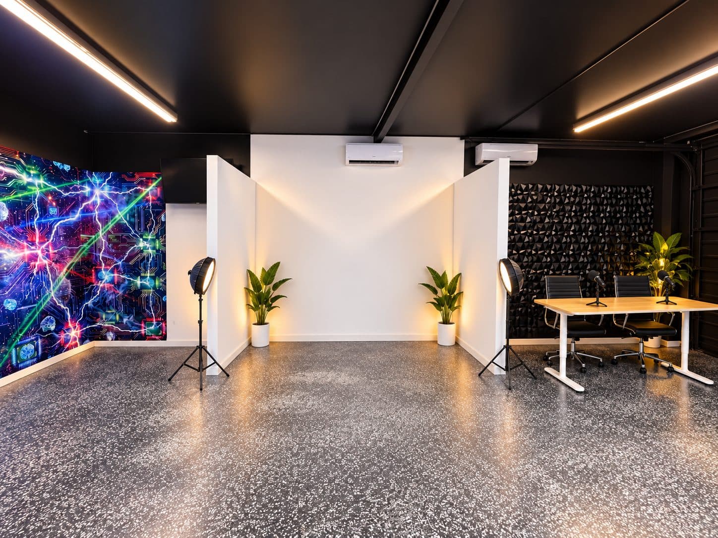 Studio floor with a neon mural wall, a white cyc corner, and a black acoustic-panel interview set